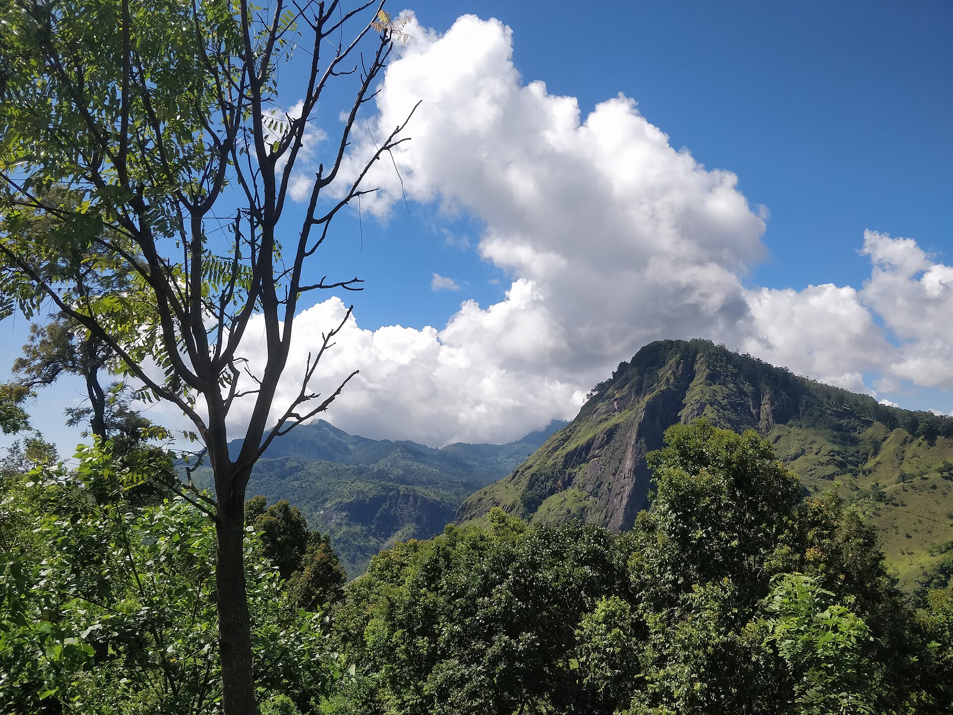 Little Adam's Peak rising above the green hills of Ella under a bright cloud filled sky